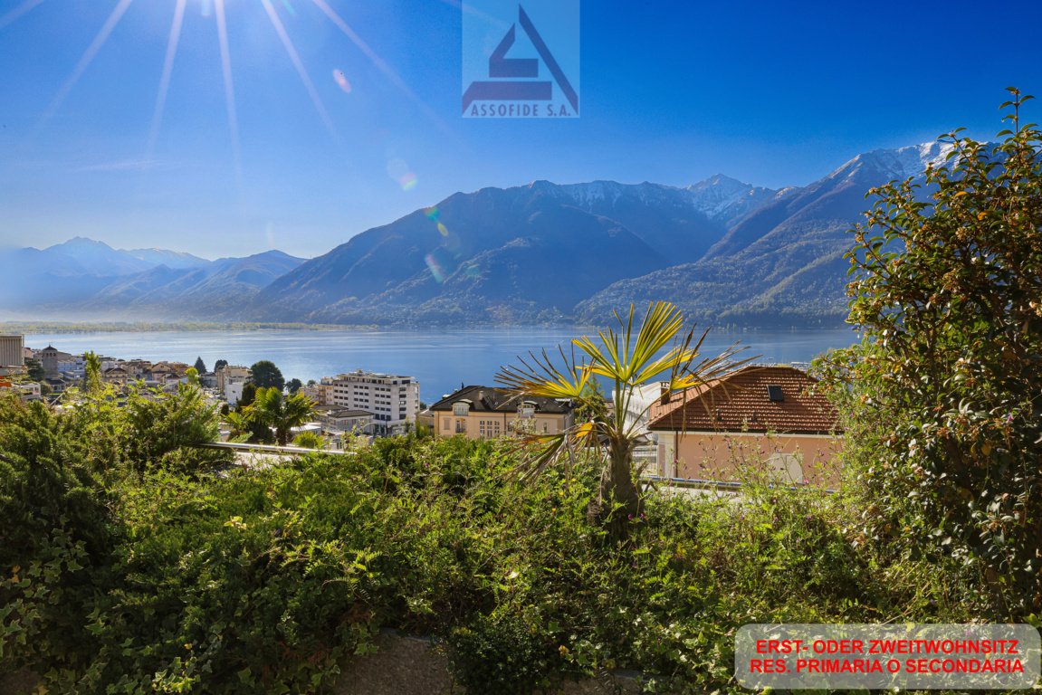 Garden with plants and trees, overlooking a lake and mountains
