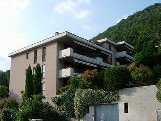 3 story building, balconies, greenery, mountain backdrop