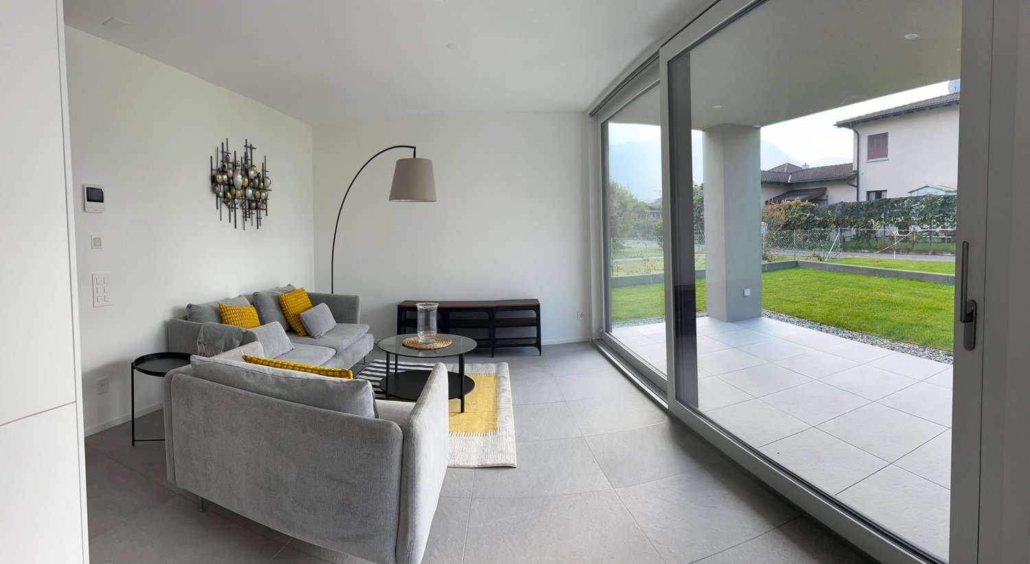 modern style living room, two grey sofas, table, decorative lamp, wall decor, sliding glass doors to balcony with a view
