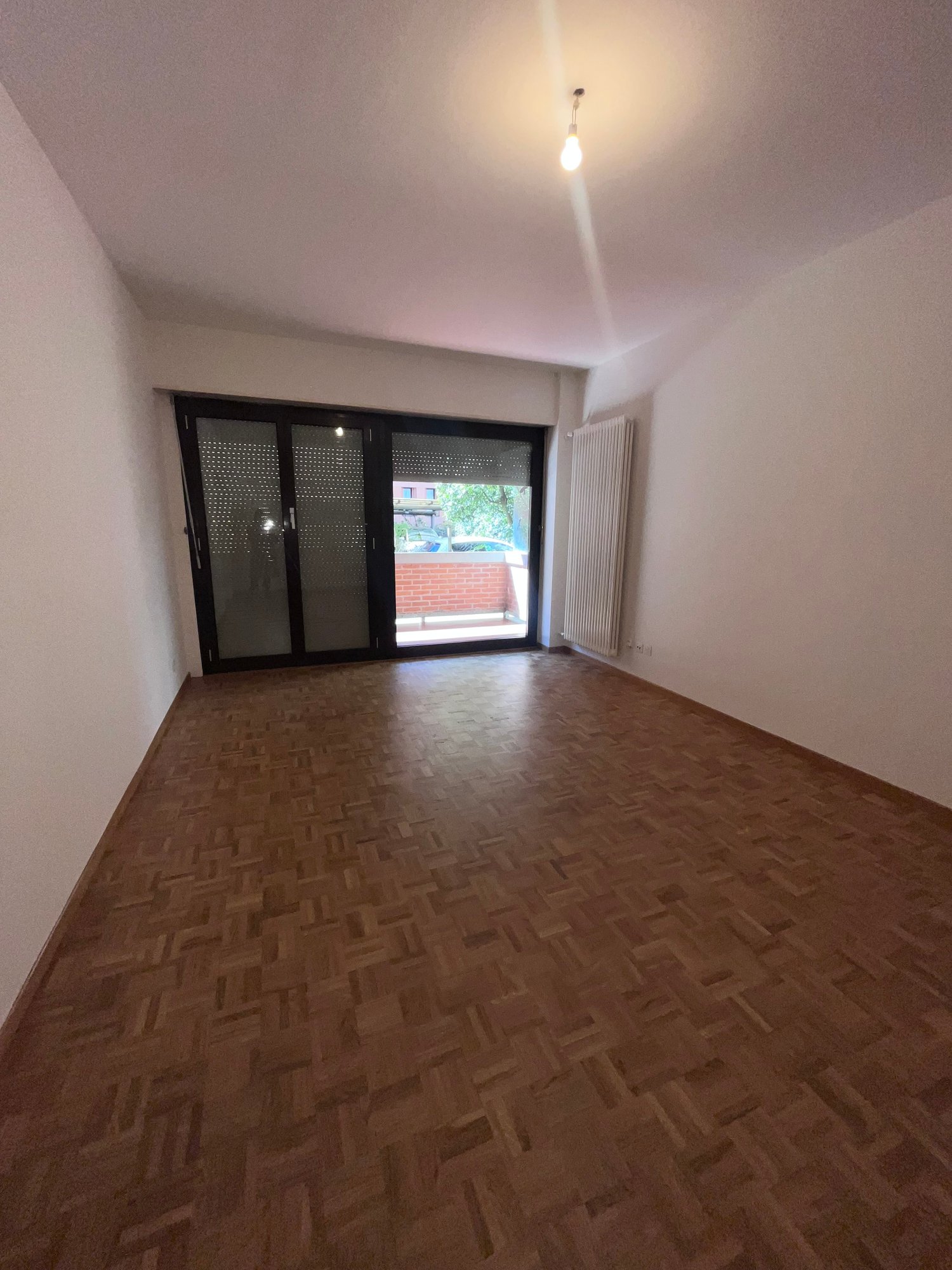 empty room, wooden floor, sliding glass door, white walls, white radiator, ceiling light