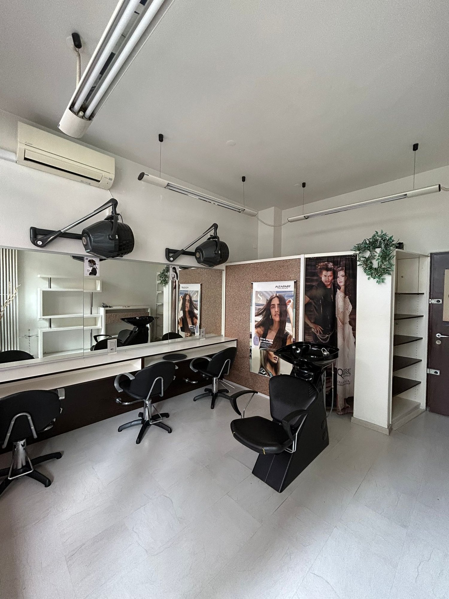 A salon space with chairs, a mirror, lamps, and a sink