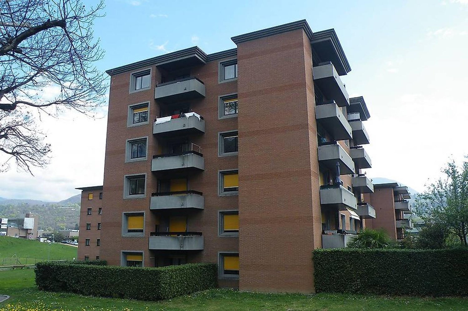 An apartment building with a modern architecture design, many balconies, and yellow windows