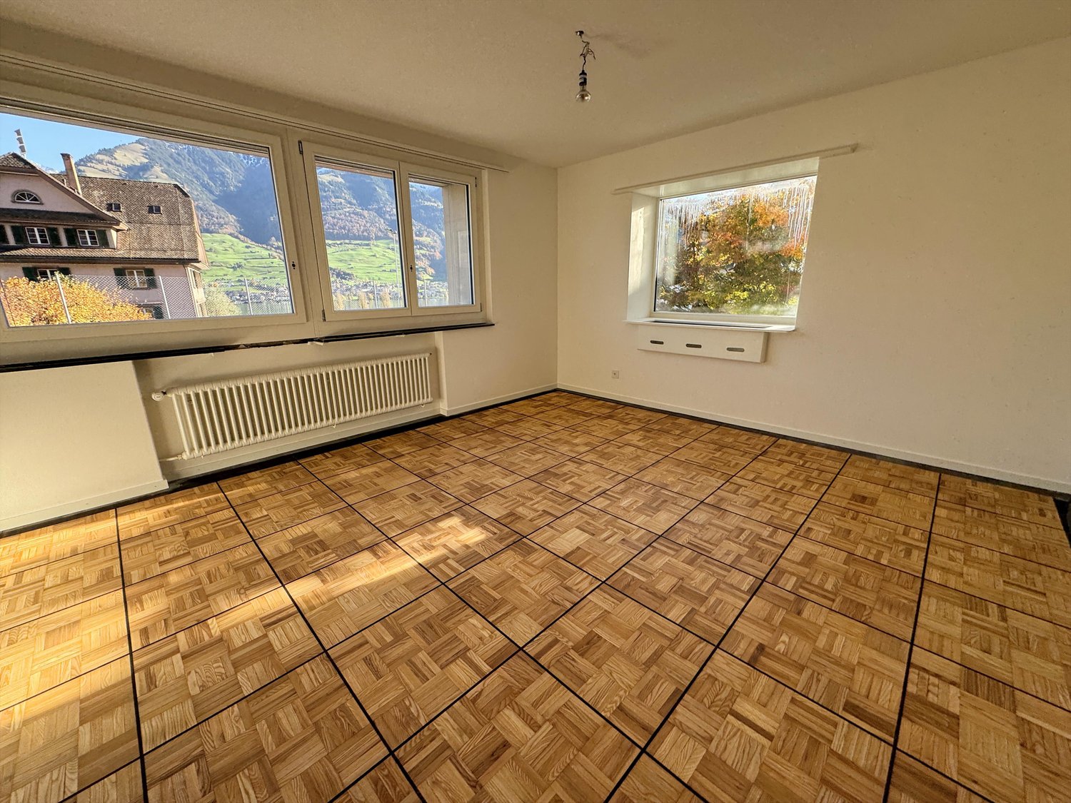 large room, parquet floor, white walls, large windows, heating radiators