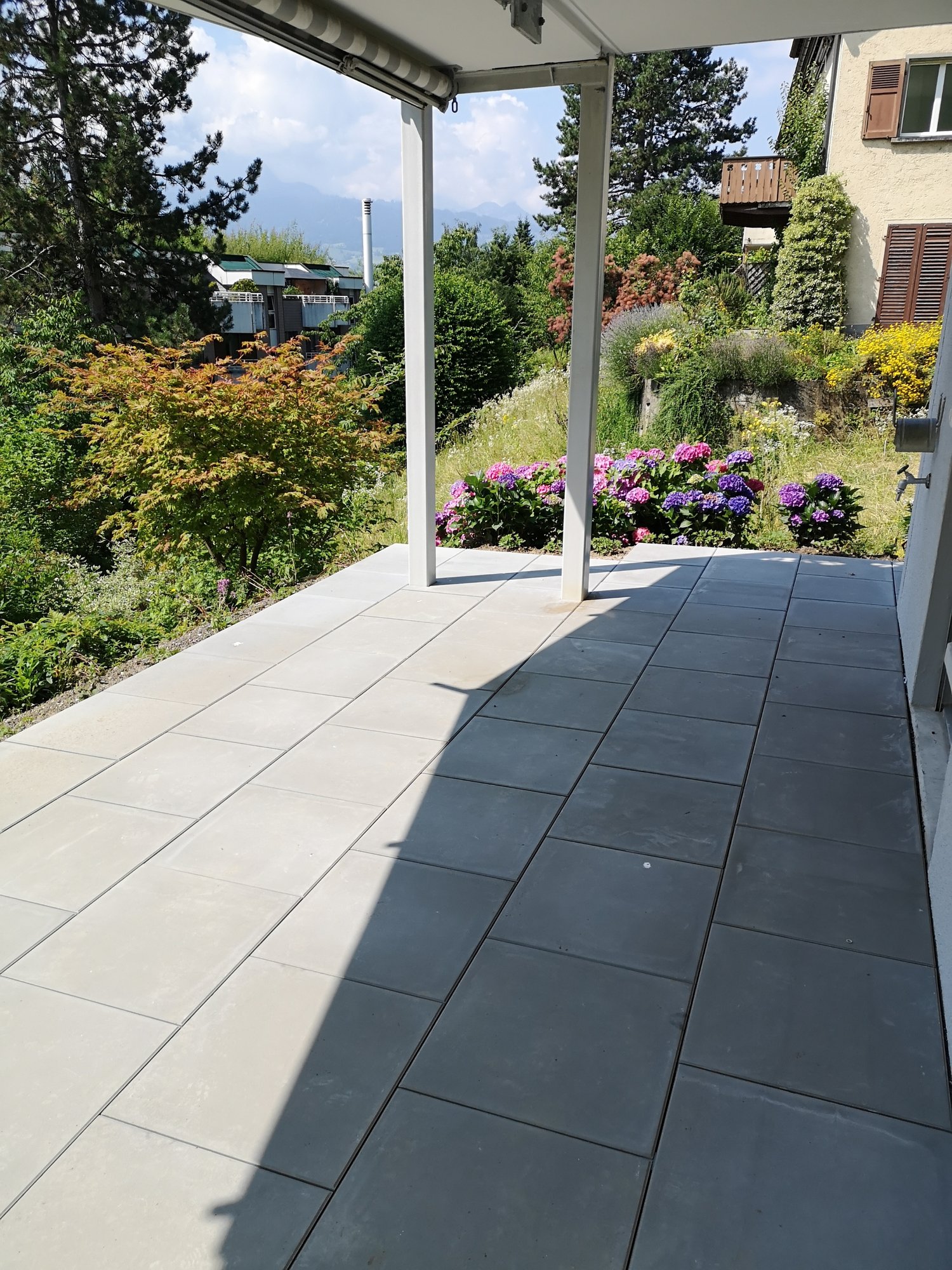 tiled balcony, outdoor table and chairs, plants in the background