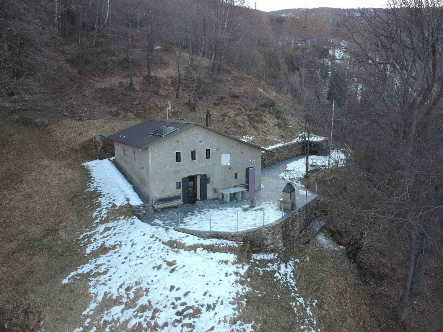 Mountain house, raised ground floor, solar panels on the roof, covered porch, garden, surrounded by trees