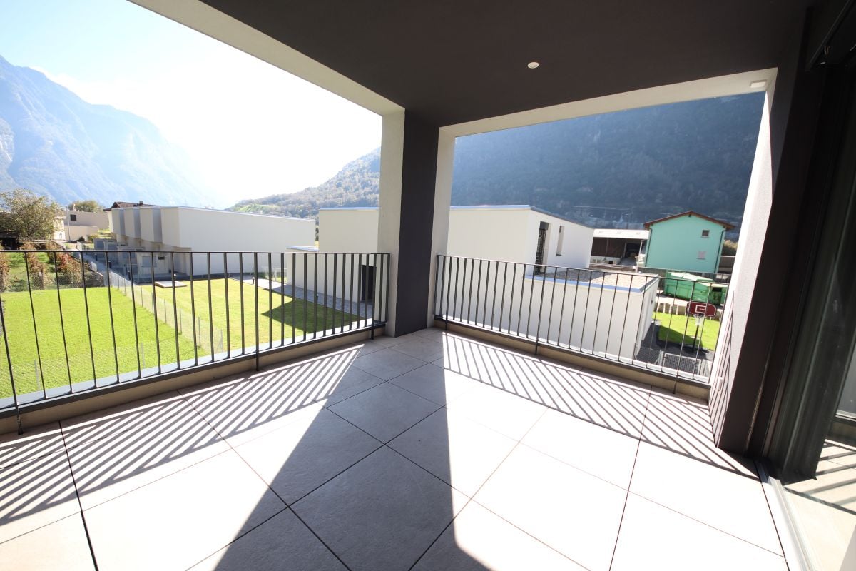 large balcony, tile floor, black railing, view of green field and mountains