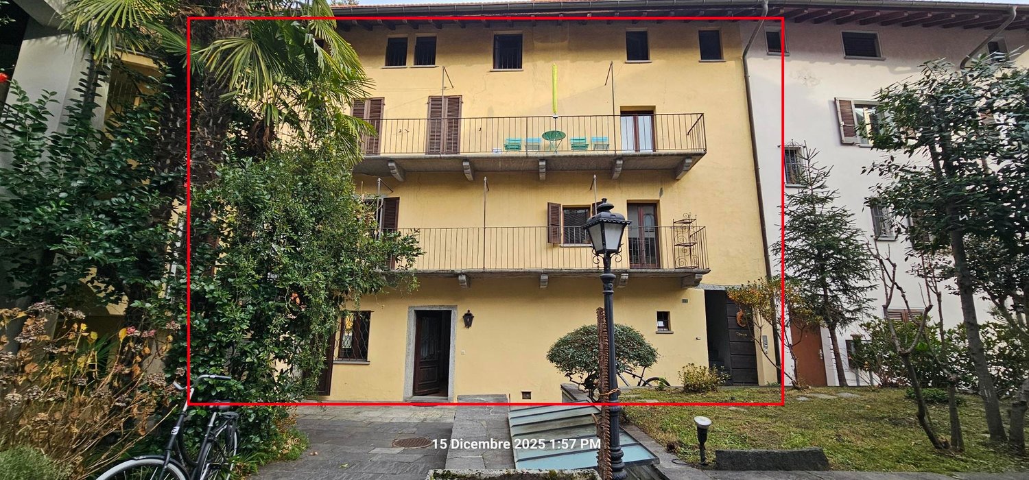 Three story house, yellow, two balconies with chairs, streetlight, entry door, bike rack