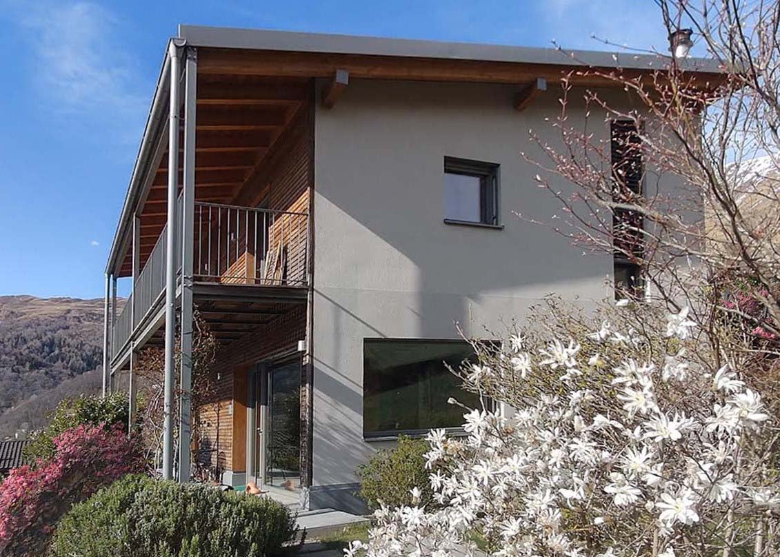 modern house, 2 stories, balcony, large windows, gray exterior, wooden accents, surrounded by greenery