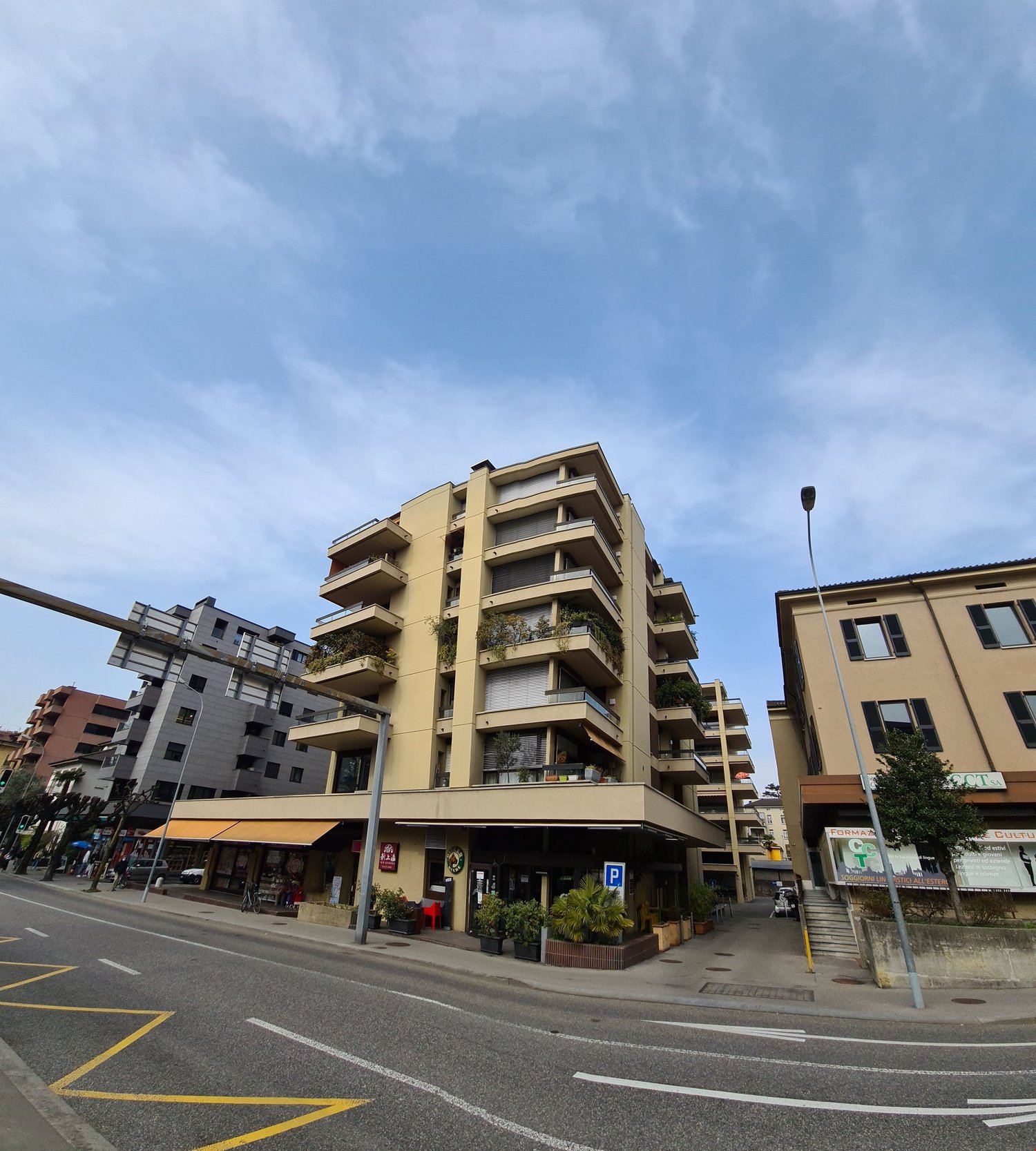 Multi-story building with balconies, storefronts, and a parking sign