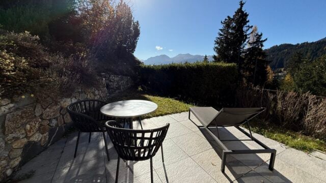 terrace, table and chairs, lounger, stone wall, greenery, mountains