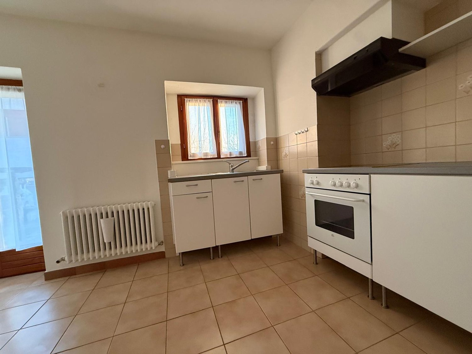 modern minimalist kitchen, white cabinets, tiled floor, gas stove, sink, wooden window frame, white radiator