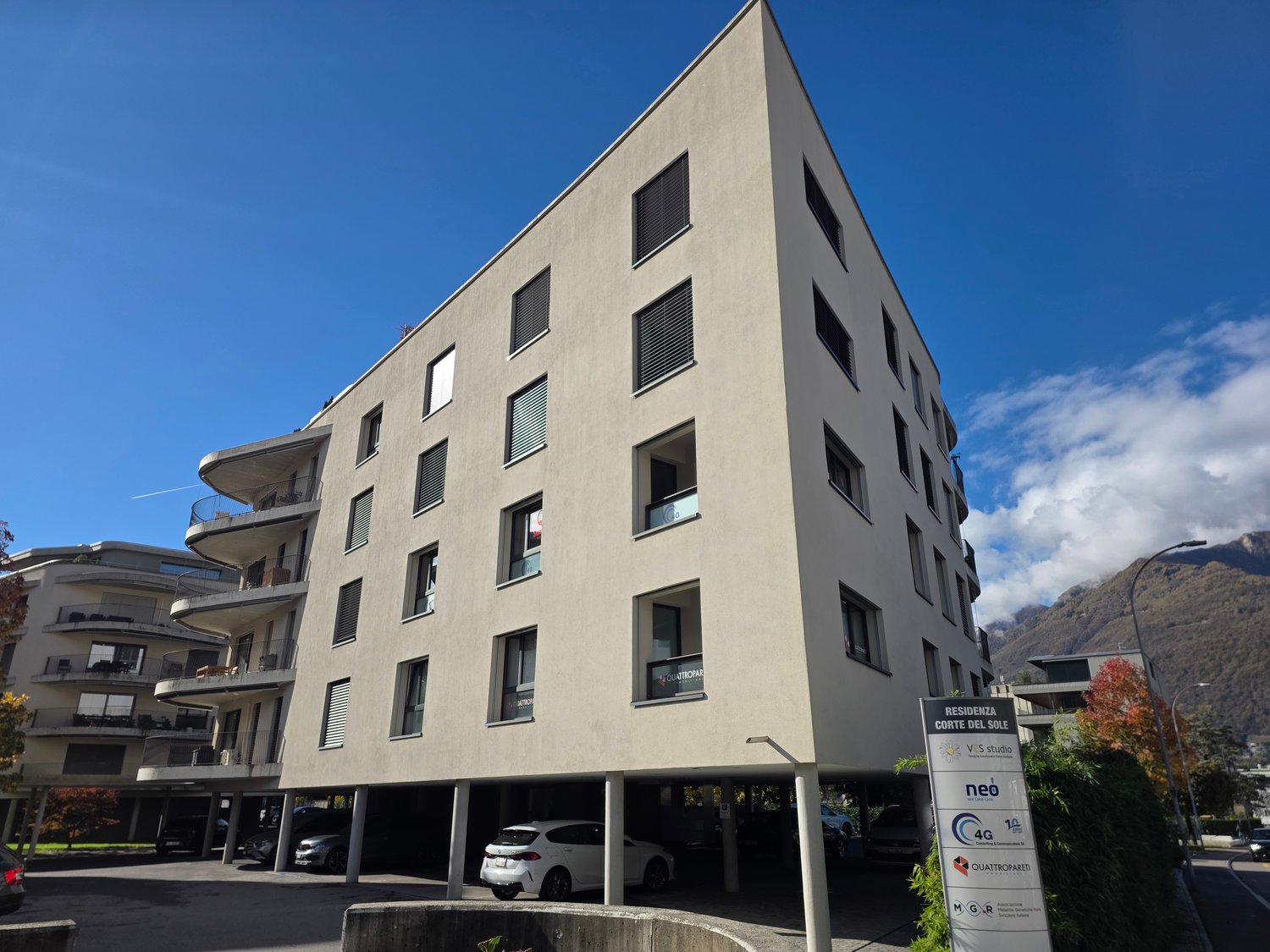 Contemporary apartment building, multiple floors, modern design, several windows, underground parking area, and signage indicating residence.