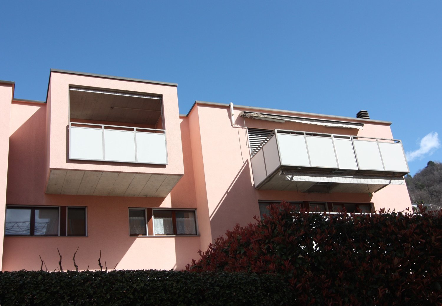 2 storey apartment building with pink exterior, two balconies
