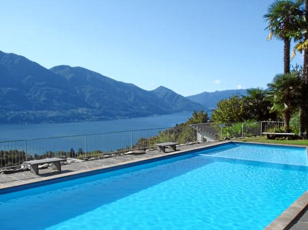 outdoor swimming pool, concrete deck, metal fence, mountains, lake