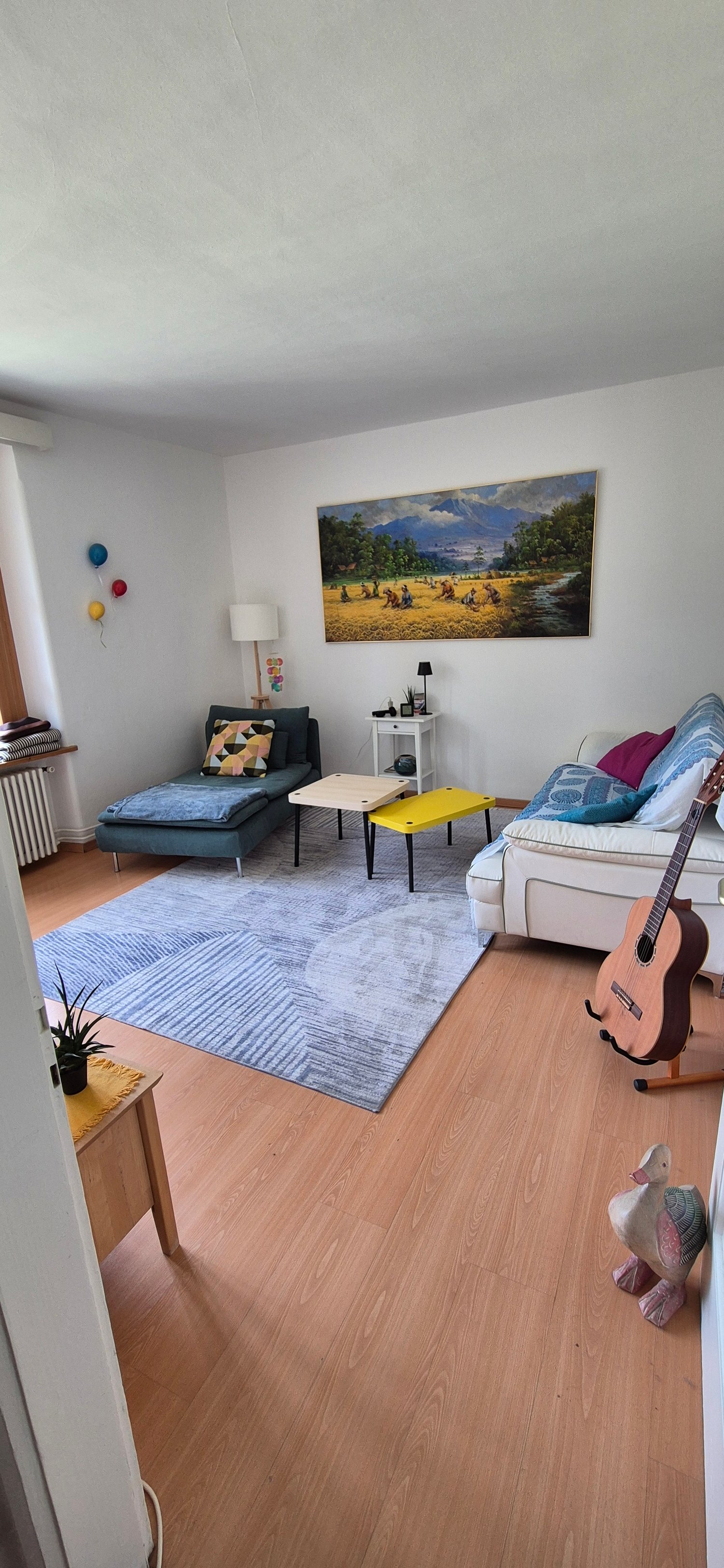 living room with two couches, coffee table, side table, rug, guitar, painting, lamp, radiator