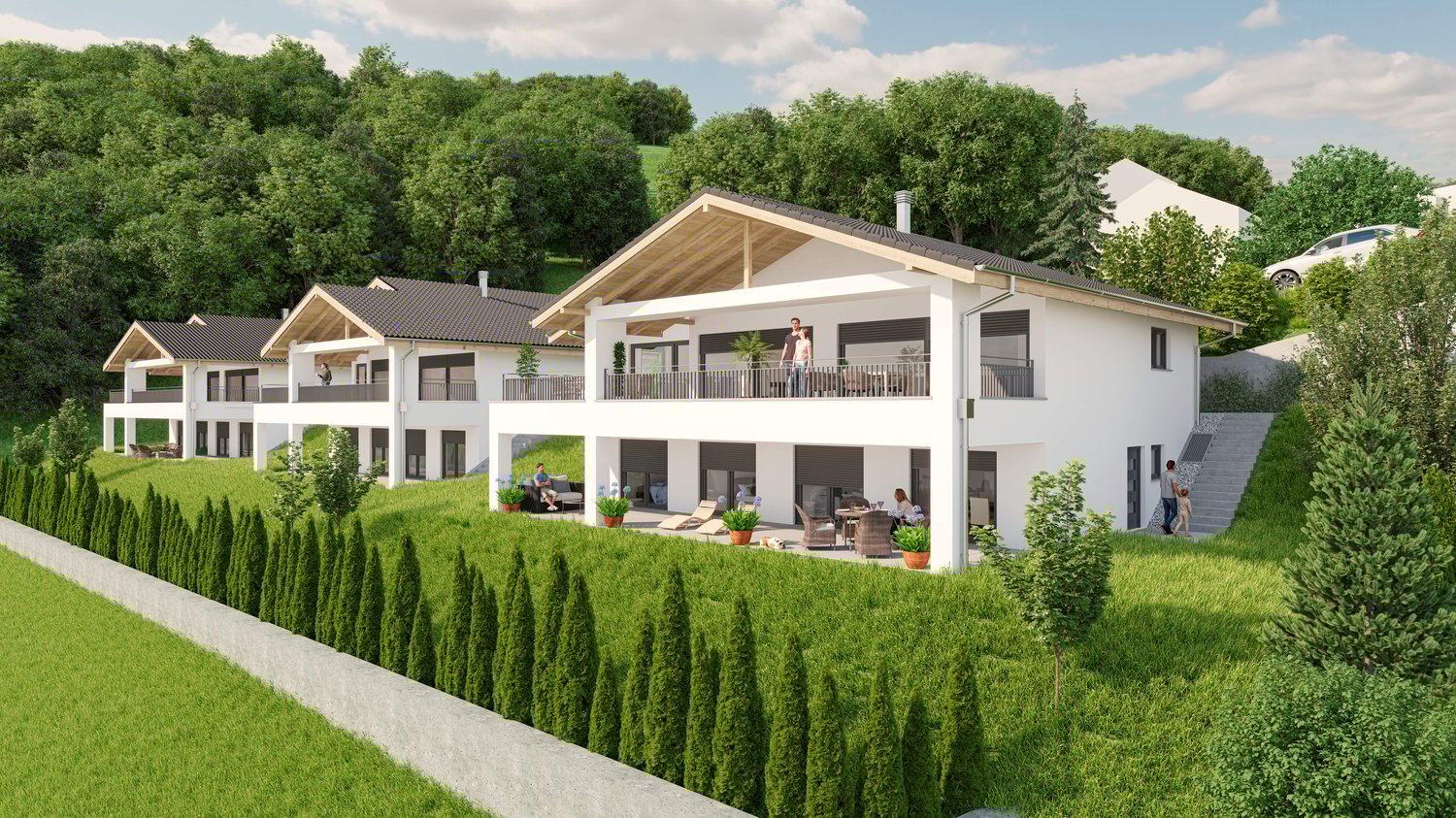 Multi-story apartment building with white exterior, slanted roofs, and balconies. The building is surrounded by lush greenery, including trees and shrubs. There is a paved driveway or parking area in front of the building.