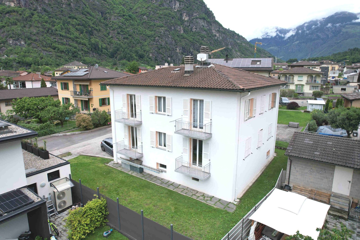 3 story house, white walls, brown roof, solar panels, balconies, mountain view