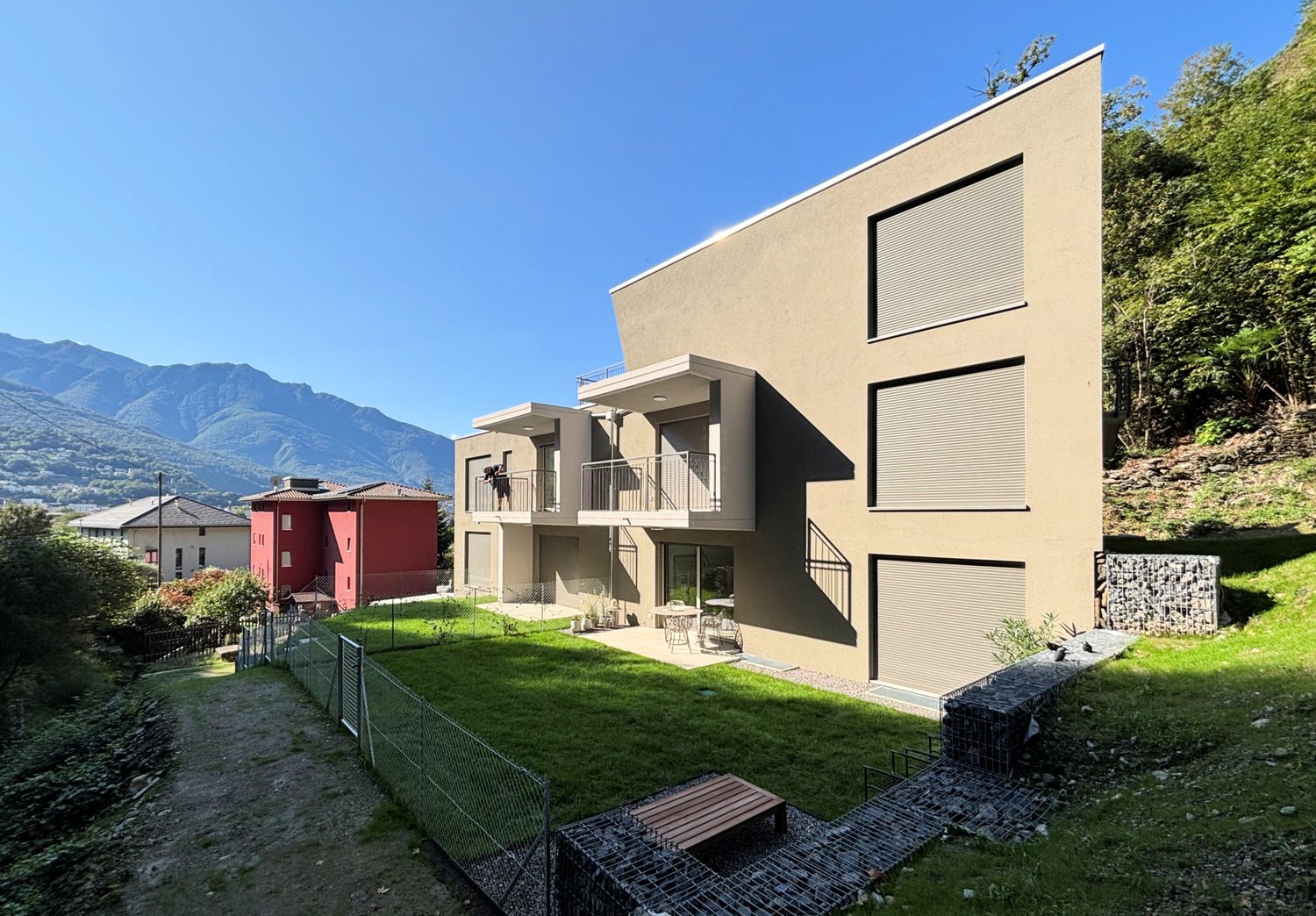Modern house, beige exterior, multiple windows, balcony, fenced yard, outdoor seating