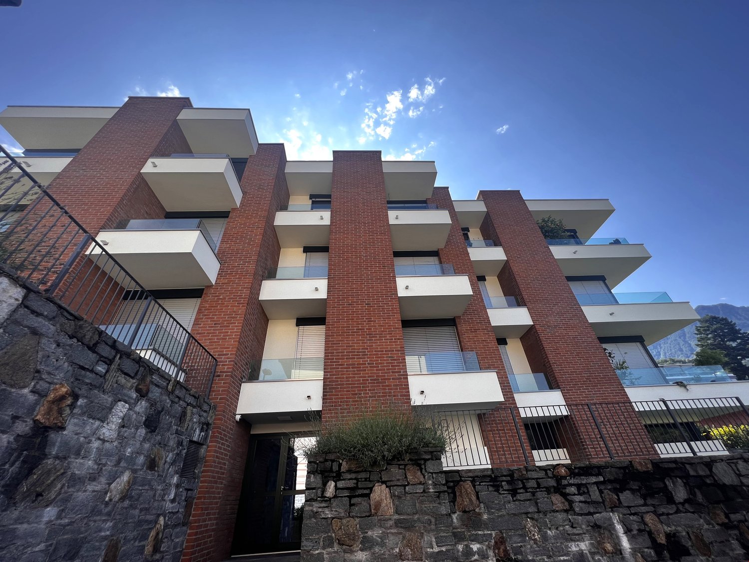 Modern brick apartment building with multiple balconies and glass railings