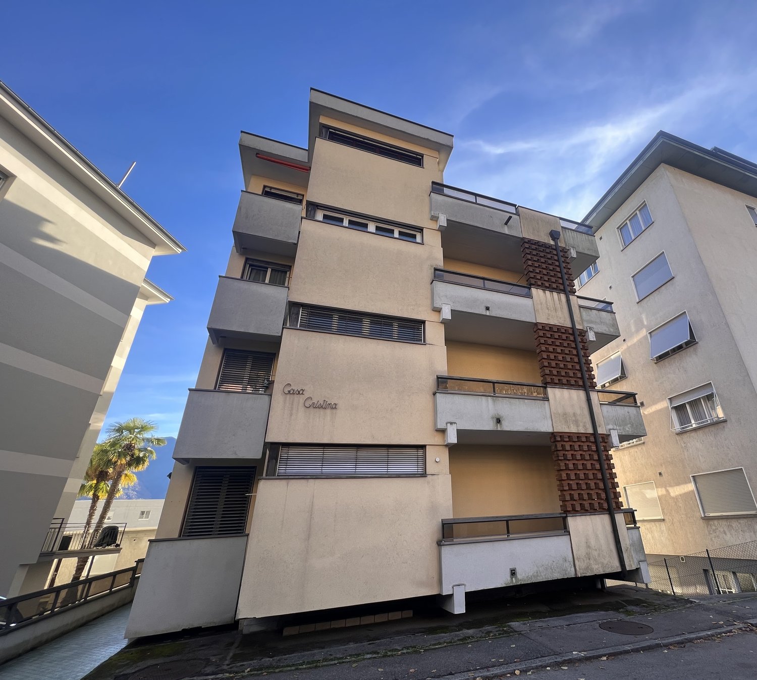 6 story building, concrete, raised ground floor, balconies, shadowed side