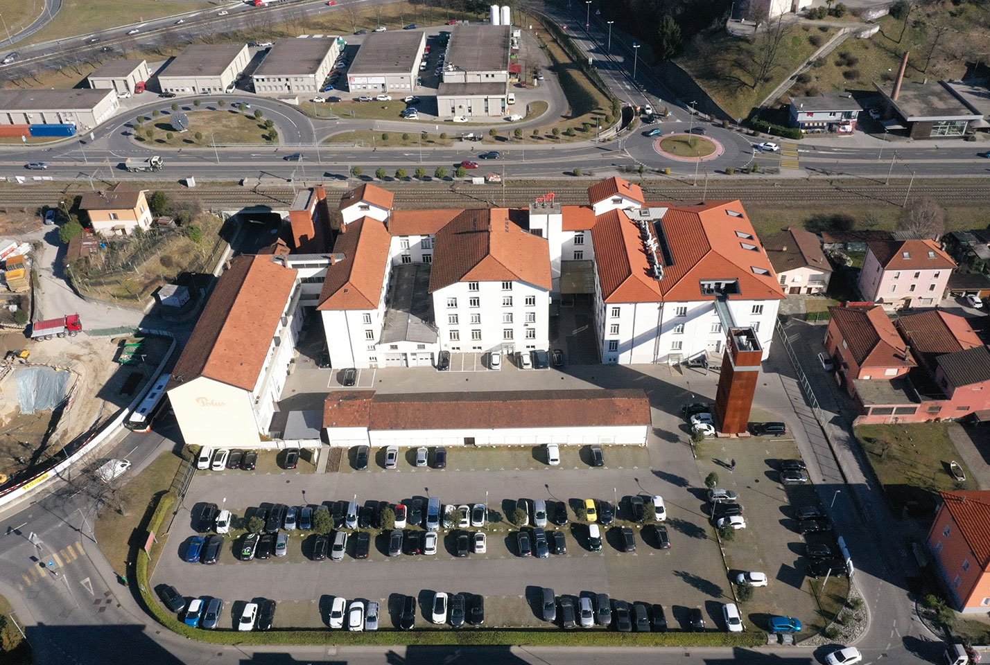 Large building with multiple wings and a central parking lot, large windows, orange roofs