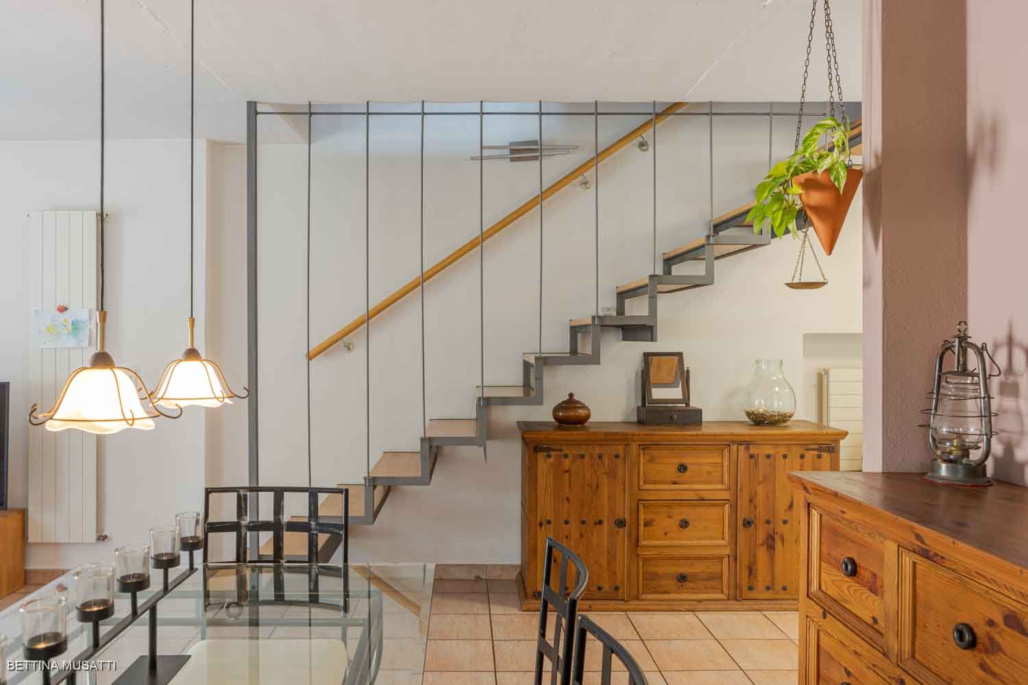 open space living area, stairs, wooden floor, dining table, chairs, kitchen cabinets, chandeliers