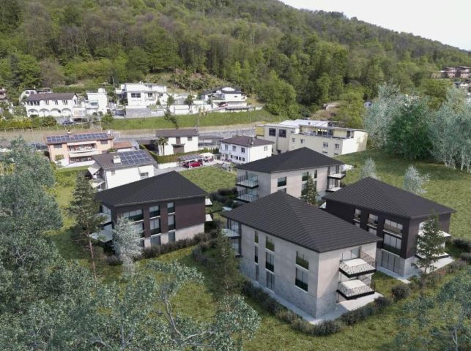 Group of modern townhouses, black rooftops, multiple balconies, surrounded by greenery, hilly background