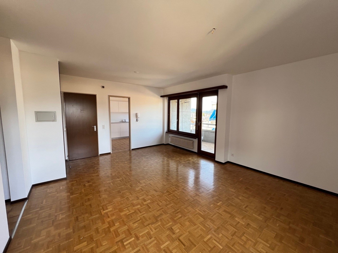 empty room, wooden floor, sliding doors, white walls, large windows, radiator, door, hallway
