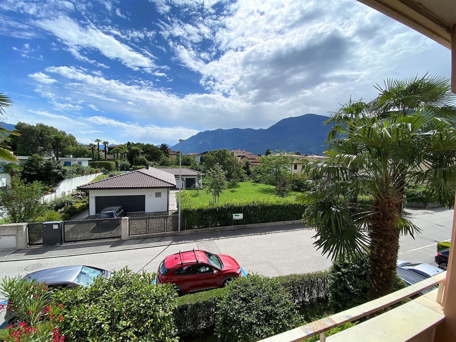 View of a suburban street with mountains in the distance, cars parked, and a house with a garage