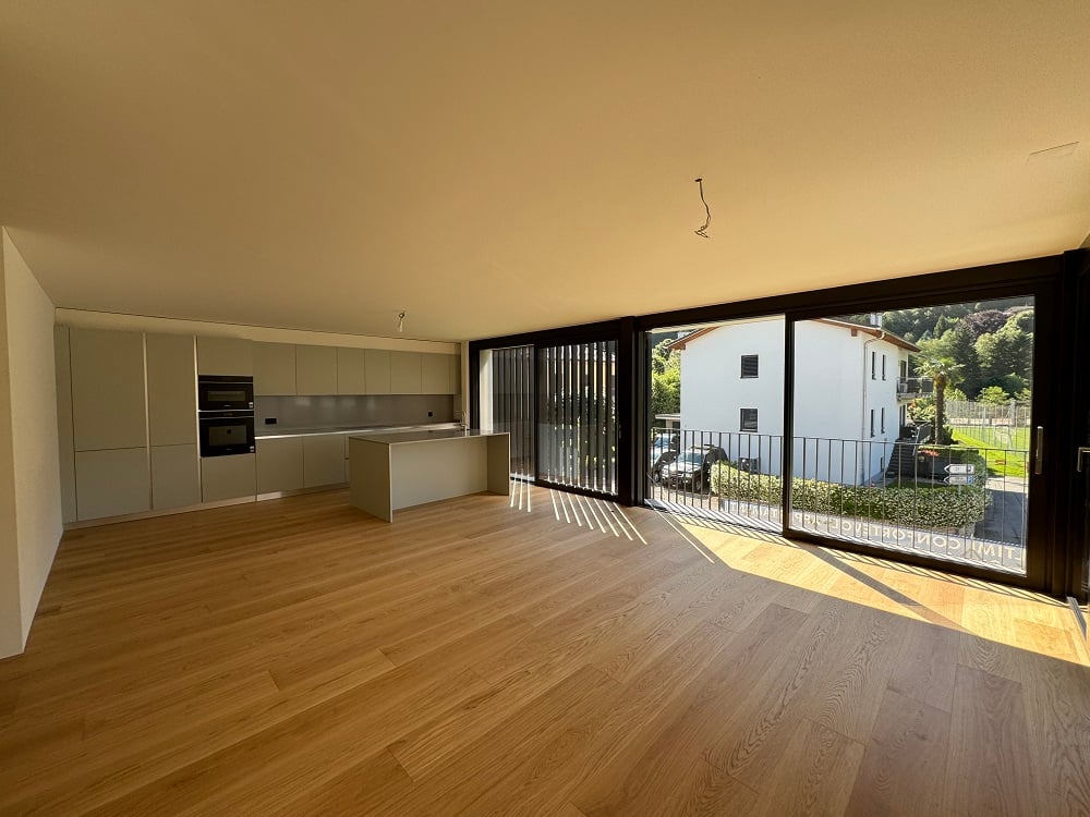 Modern kitchen with countertops, wooden floors, glass sliding doors leading to balcony