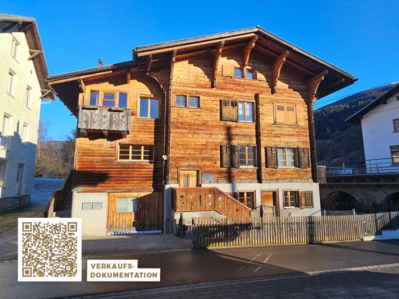 Large wooden house with several floors, wooden balcony, and a staircase leading to the entrance.