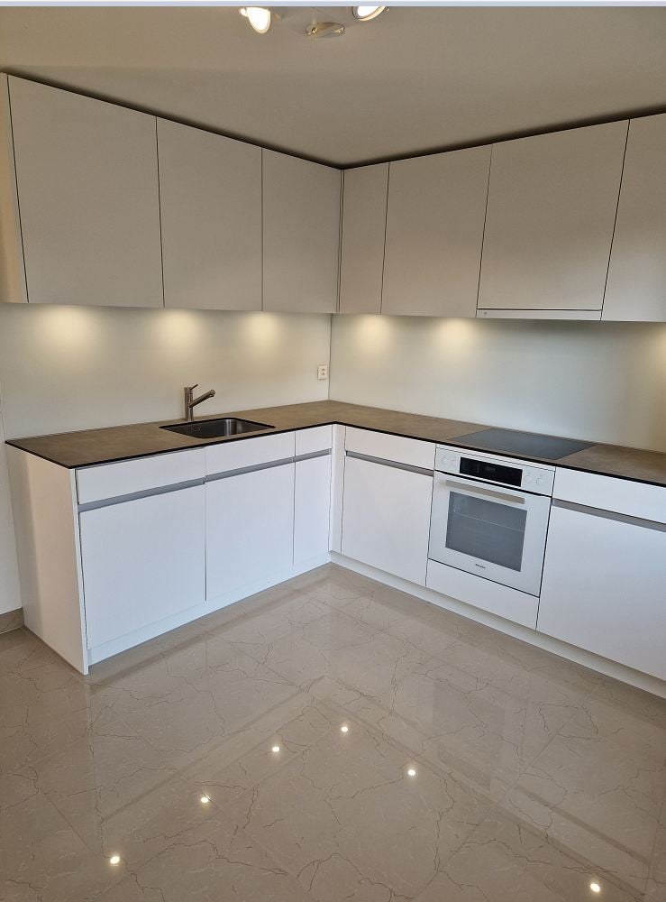 modern kitchen with white cabinets, granite countertop, stainless steel sink, built-in oven and stove, under-cabinet lighting
