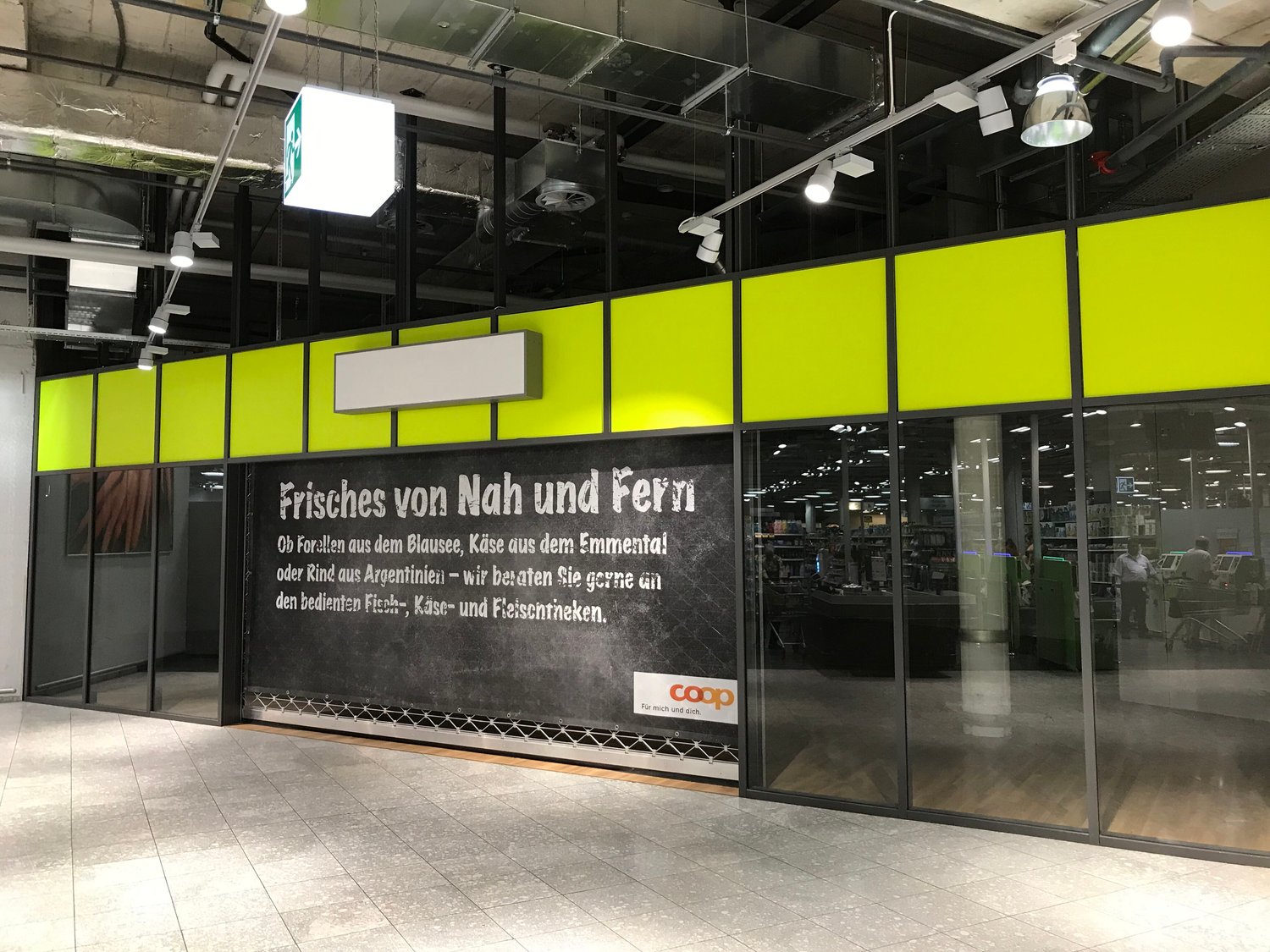 Yellow and green panels with a glass entrance and an advertising banner for 'coop'