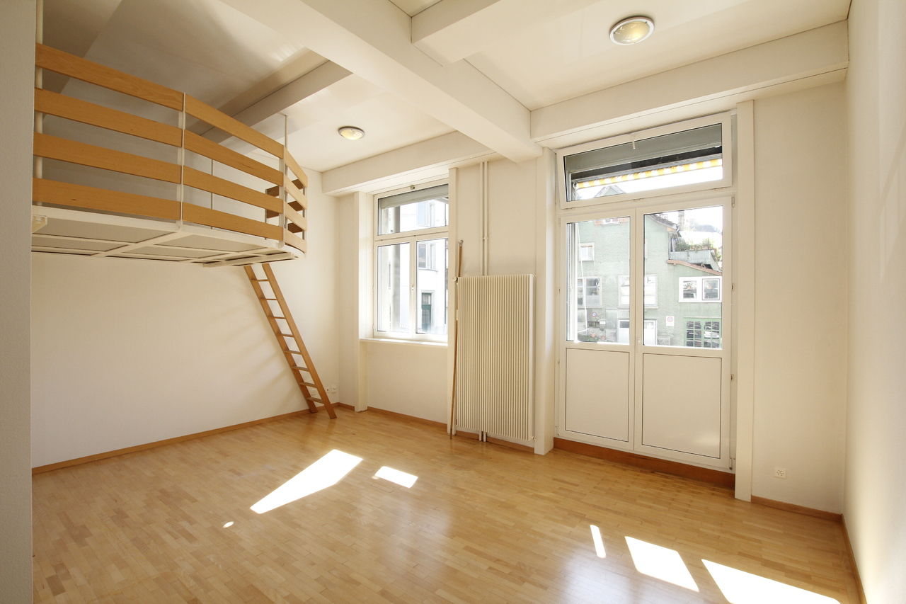 empty room, raised floor, hardwood floors, wooden ladder, two windows, one door