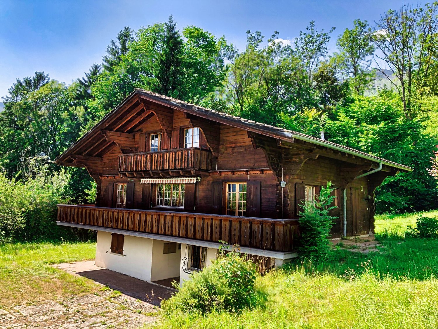 Traditional wooden house, 2 story, balcony, surrounded by greenery