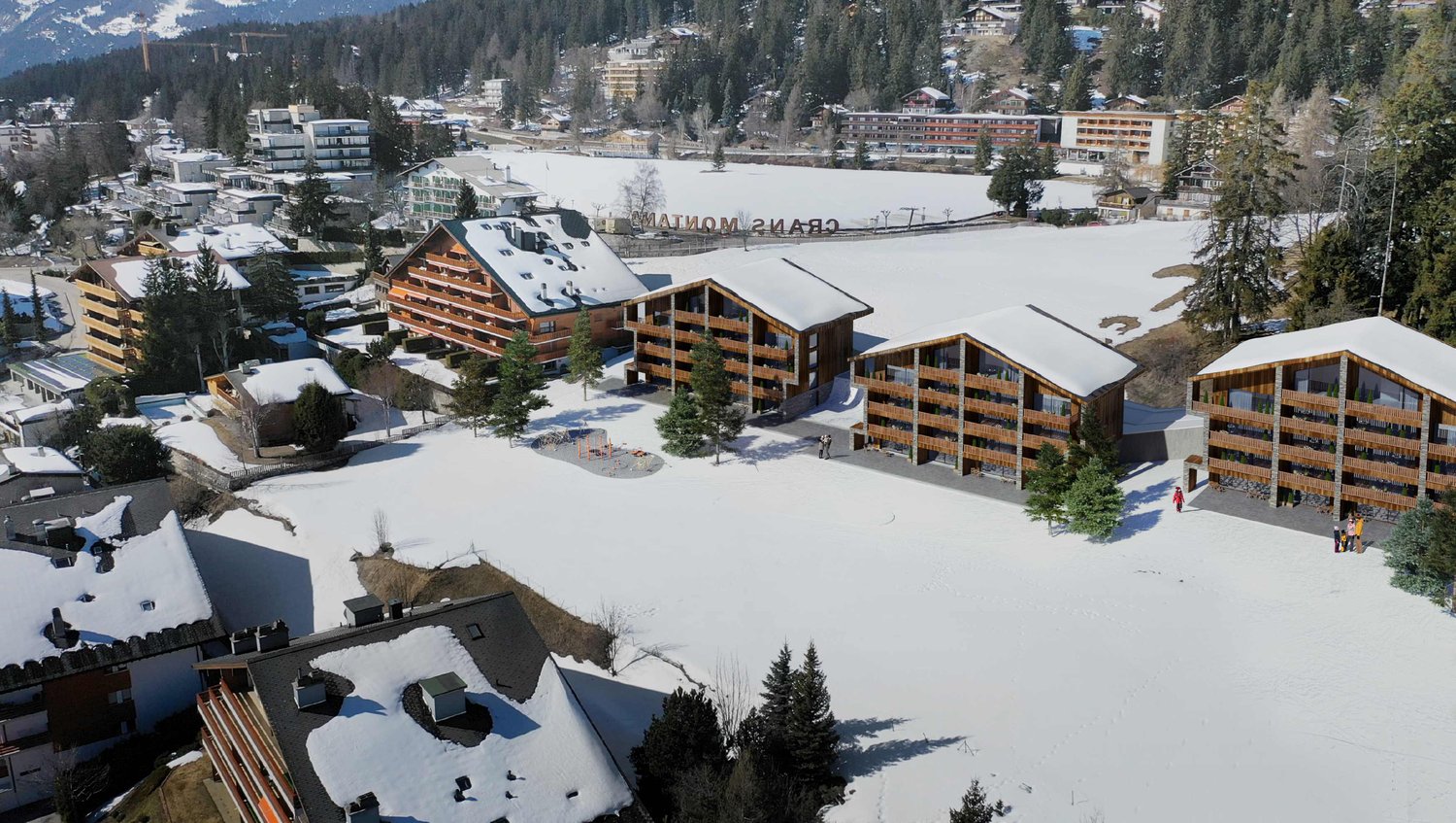 Buildings with snow-covered roofs, large windows, wooden design, surrounded by a snowy landscape with trees and mountains