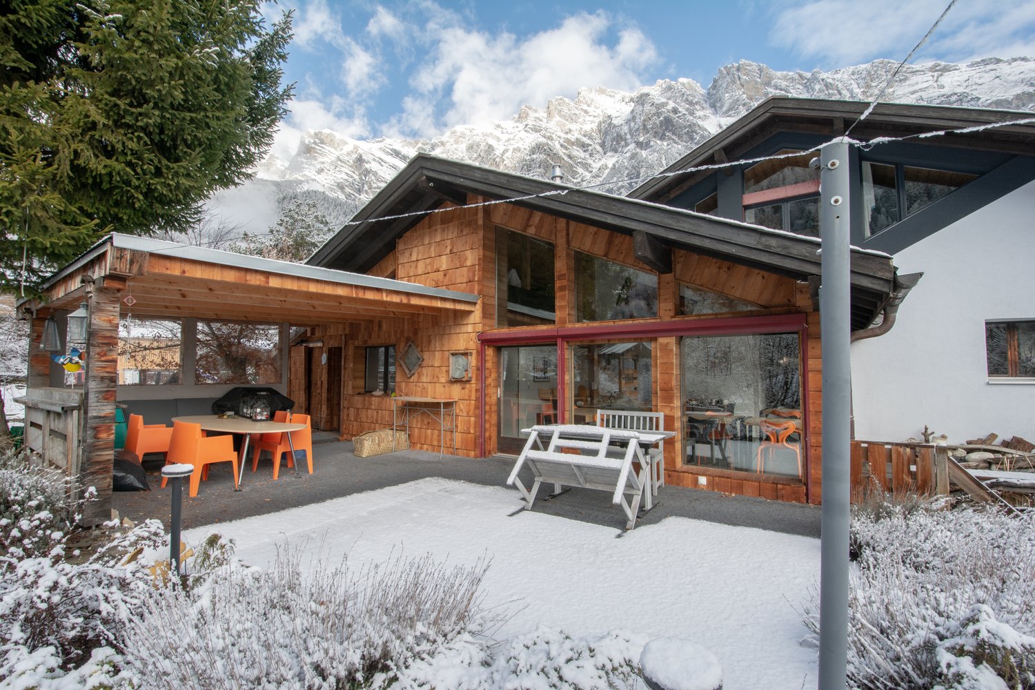 Modern wooden house with raised ground floor, terrace, covered porch, snow-covered surroundings