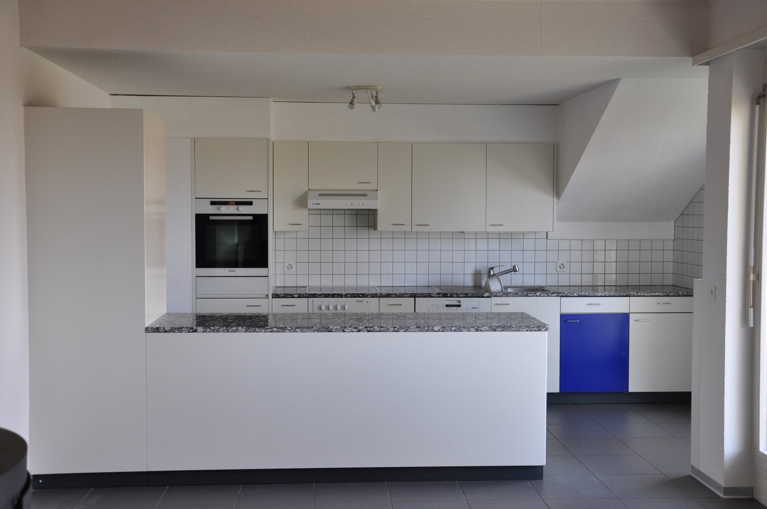 fully equipped kitchen, white cabinets, white appliances, white walls, white tiled walls, large island with granite countertop