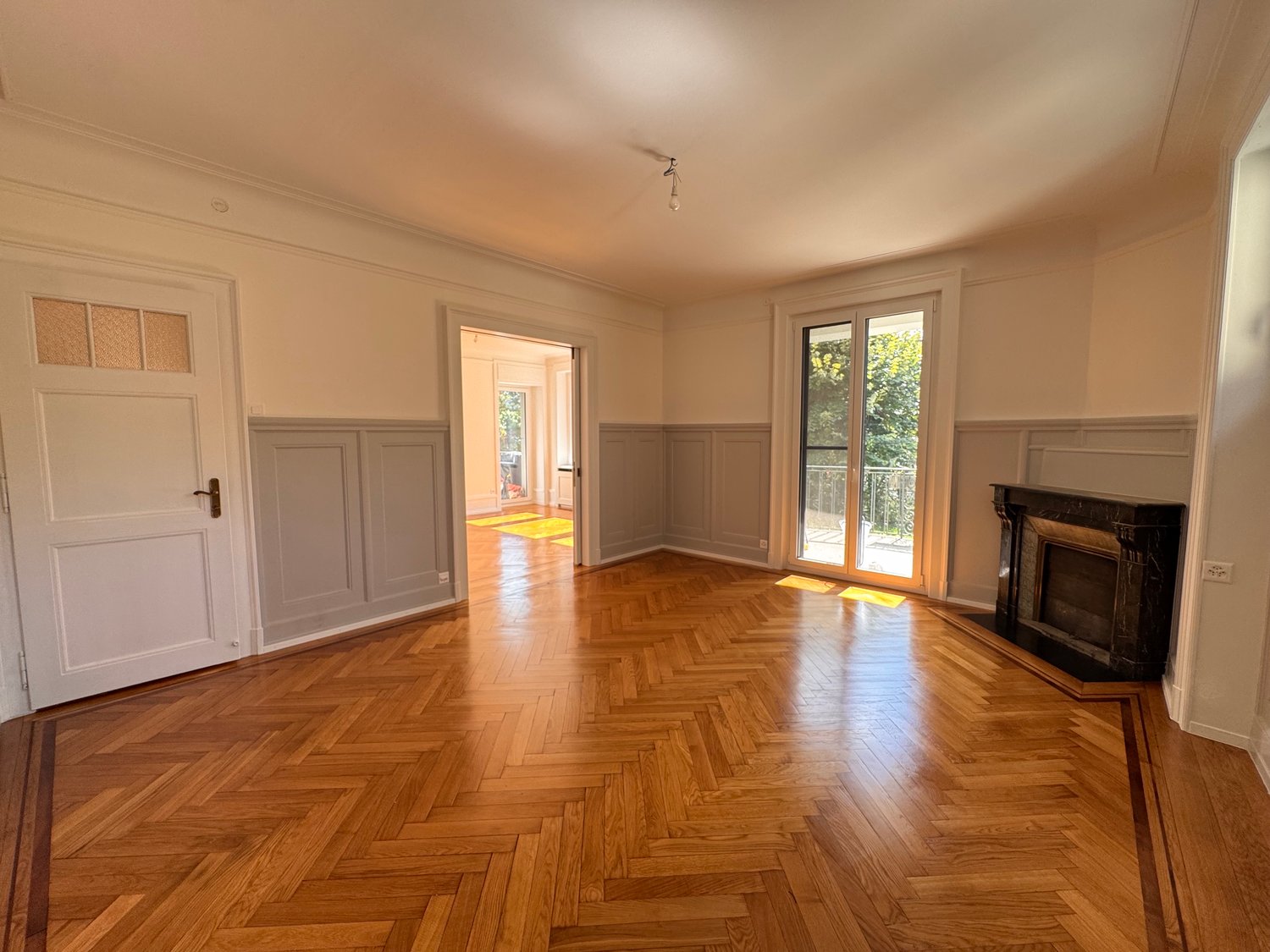 Empty room with hardwood floors, fireplace, double glass doors, sliding door, and white walls.