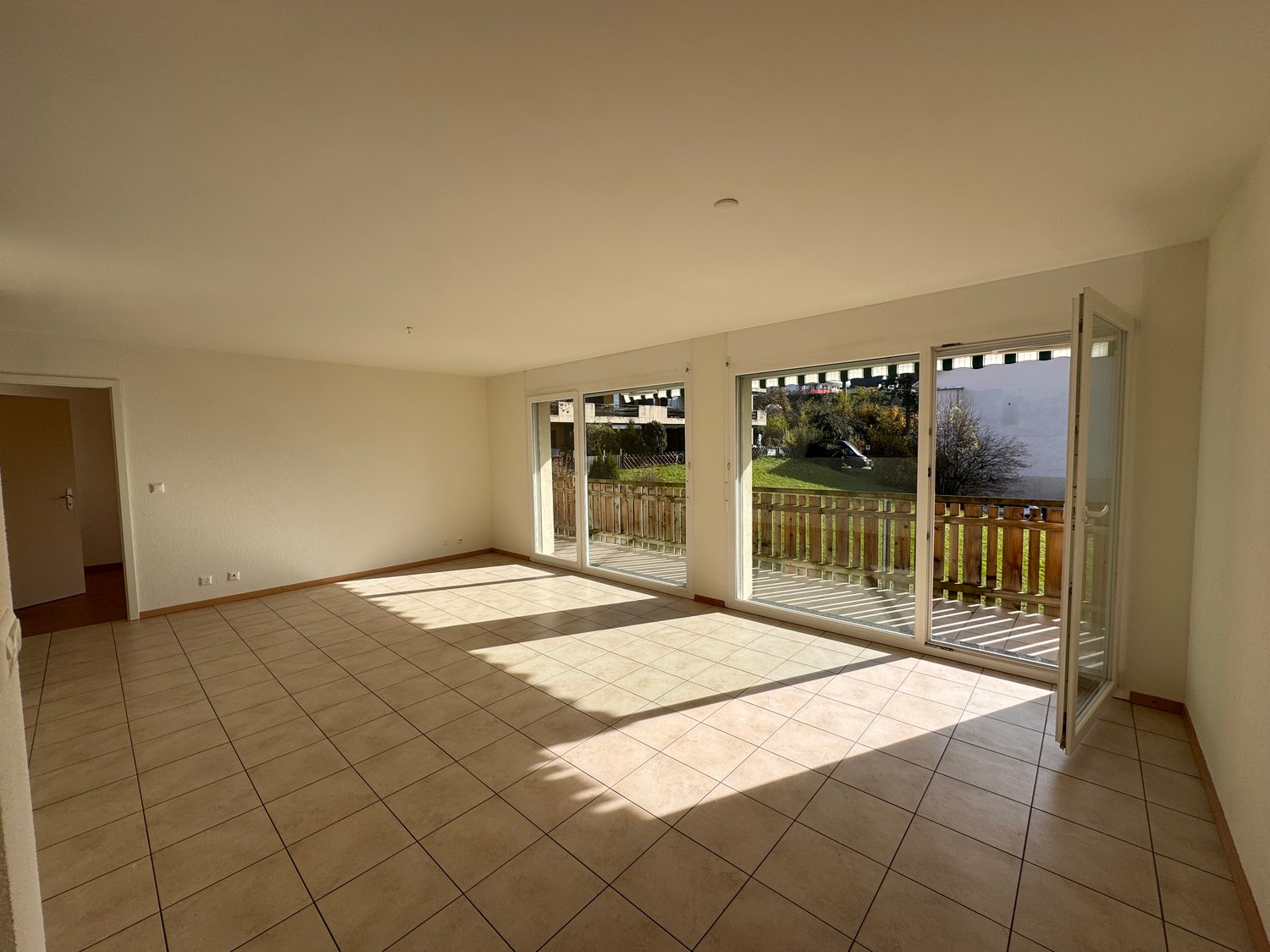 Empty room with sliding doors, tile flooring, white walls, balcony