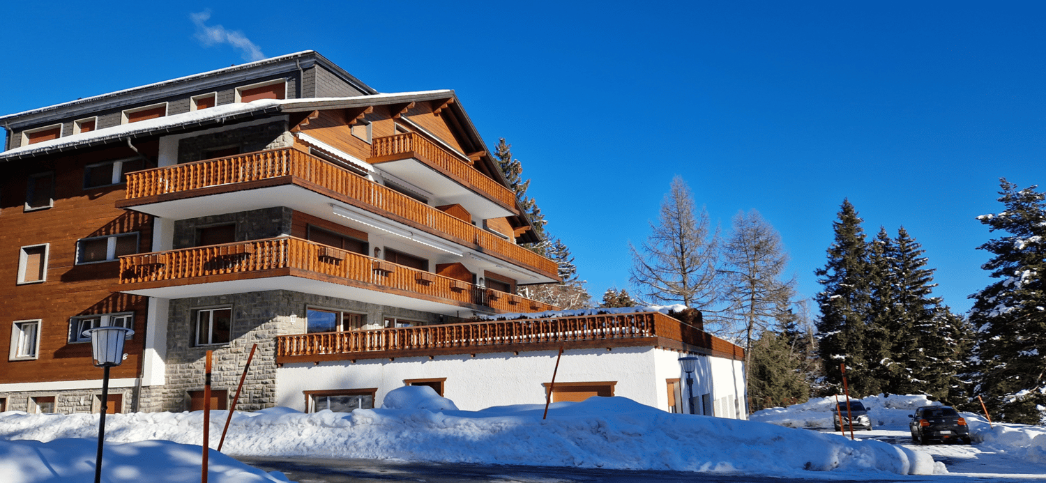 Modern multi-level building, wooden balconies, brick facade, snow-covered ground