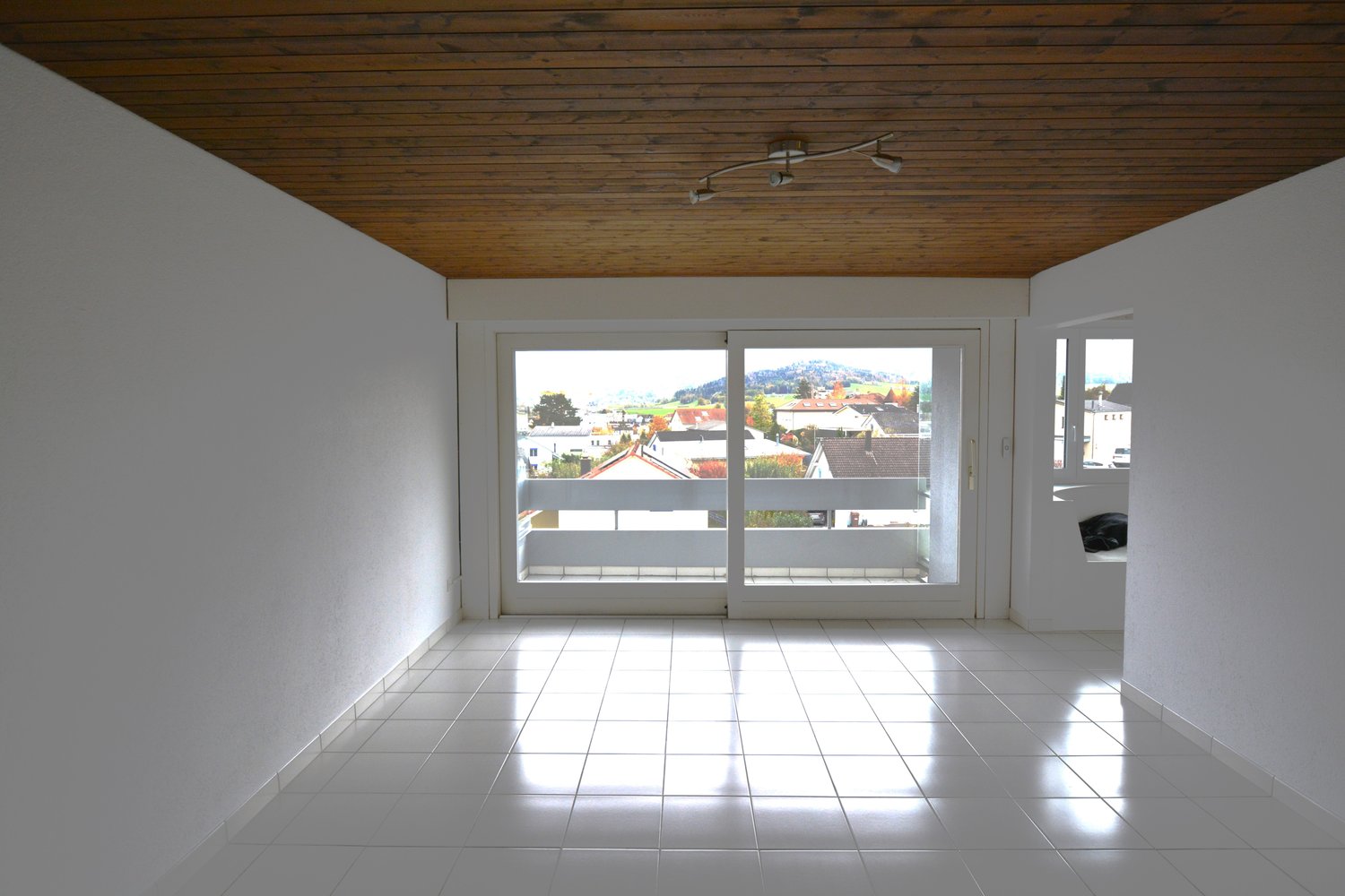 white tile floor, large windows with balcony, wooden ceiling, view of the town