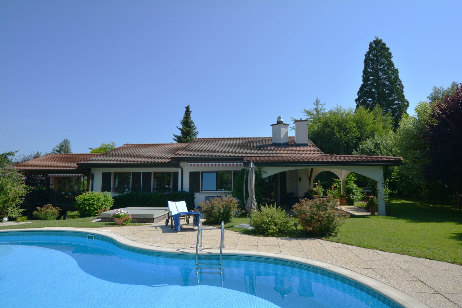 Modern house with swimming pool, outdoor seating, well-kept garden