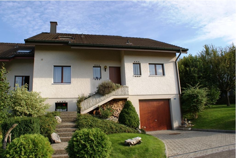 2 story house, white stucco, brown windows, brown door, stone driveway, stairs leading to wooden front door, garage