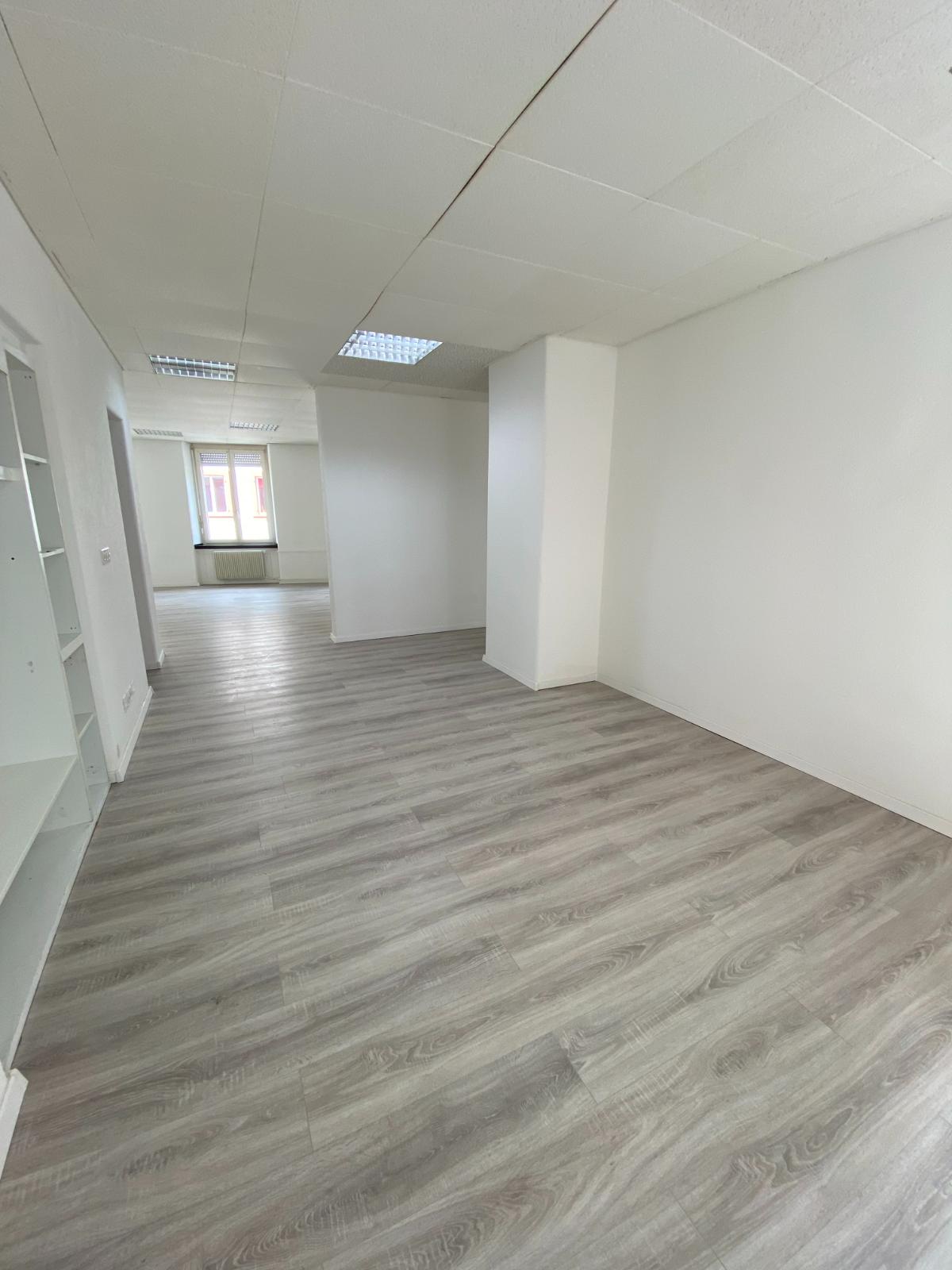 Empty room, hardwood floors, white walls, high ceilings, two columns, windows