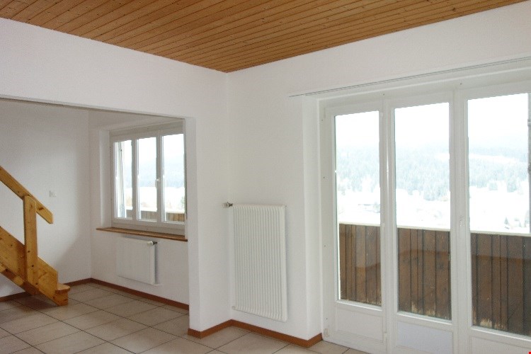 white walls, large windows, balcony, radiators, wooden stairs, tiled floor