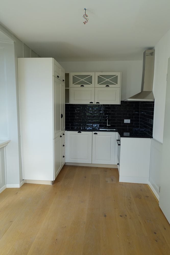 modern kitchen, black tiled backsplash, white cabinets, stainless steel sink, wooden floor