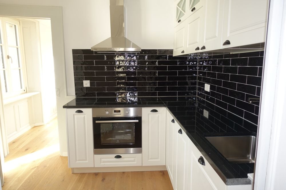 kitchen, white cabinets, black tiled countertops, stainless steel oven and extractor, stainless steel sink