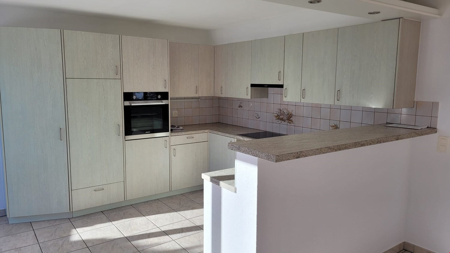 open kitchen, white cabinetry, tiled backsplash, oven, dishwasher, countertop