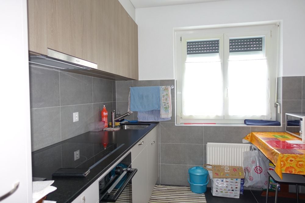 white cupboards, grey tiles, black counter, window, power outlet, blue towels